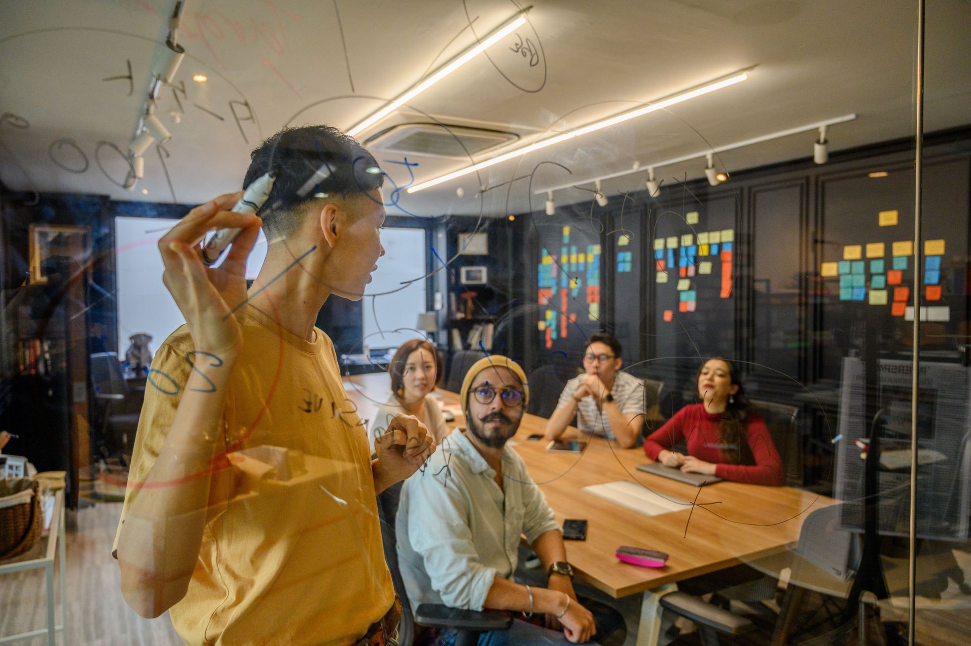 A team working through ideas on a glass whiteboard in a strategy session